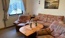 Das Wohnzimmer mit gemütlicher Couchgarnitur und TV sowie einer Essecke und Zugang zum Balkon