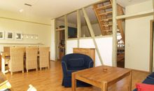Der urig-gemütliche Wohnbereich mit Sitzecke, Essecke und alten Holzbalken zur Raumtrennung
