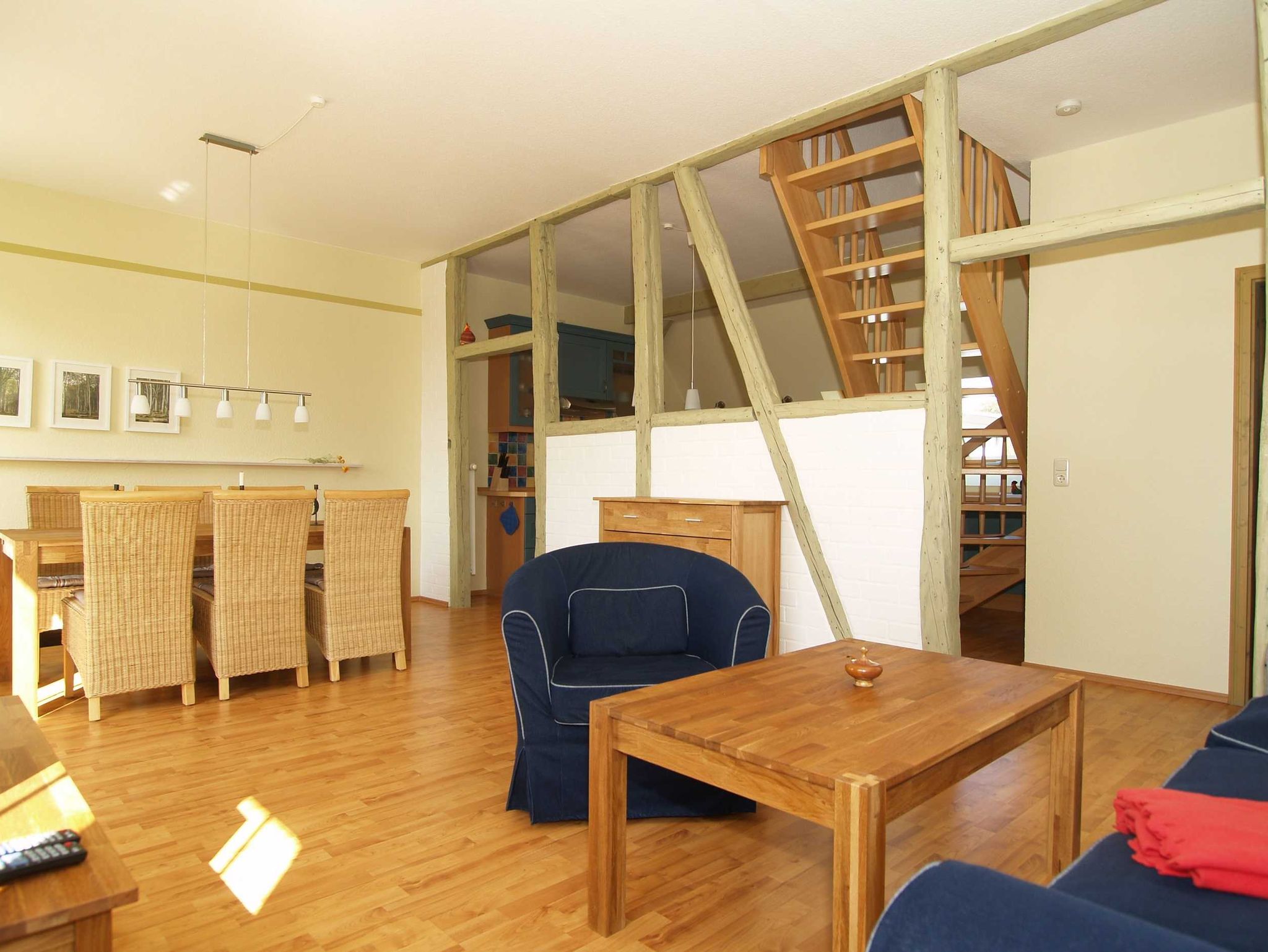 Der urig-gemütliche Wohnbereich mit Sitzecke, Essecke und alten Holzbalken zur Raumtrennung