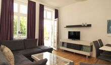 Der Wohnbereich mit gemütlicher Couchgarnitur, Flachbild-TV und Zugang zum möblierten Balkon