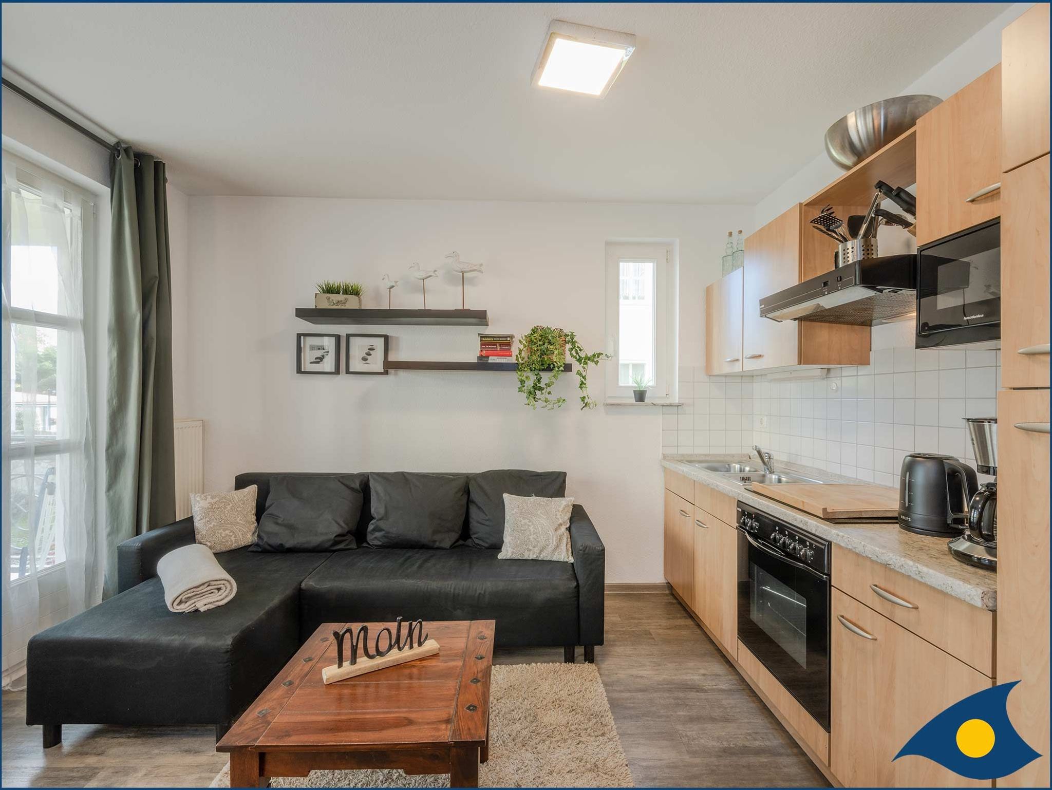 Wohnzimmer mit Küchenzeile und Zugang zum Balkon